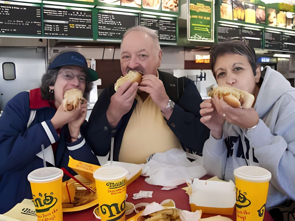 Three people eating hot dogs at Nathans