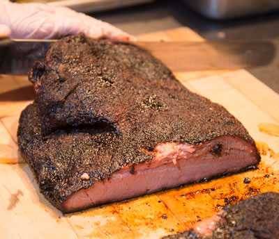 Barry Sorkin removing fat from a cooked brisket.